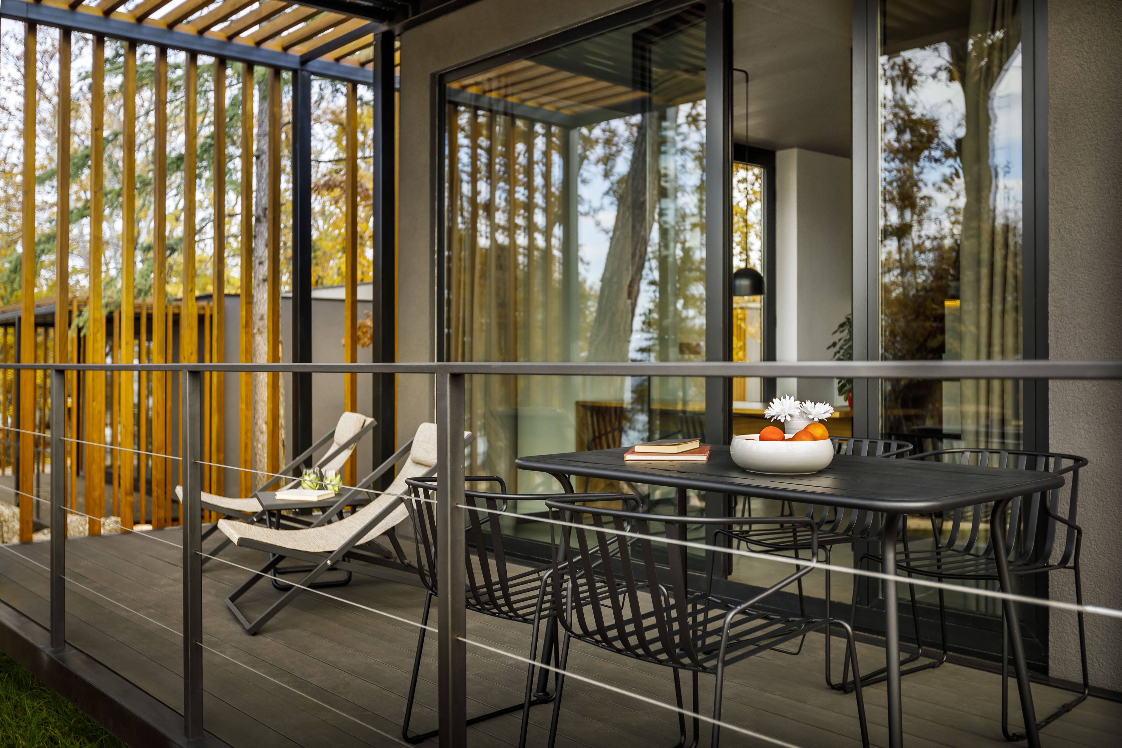 Un patio al aire libre con una mesa y sillas, una cerca de madera y vistas a árboles.