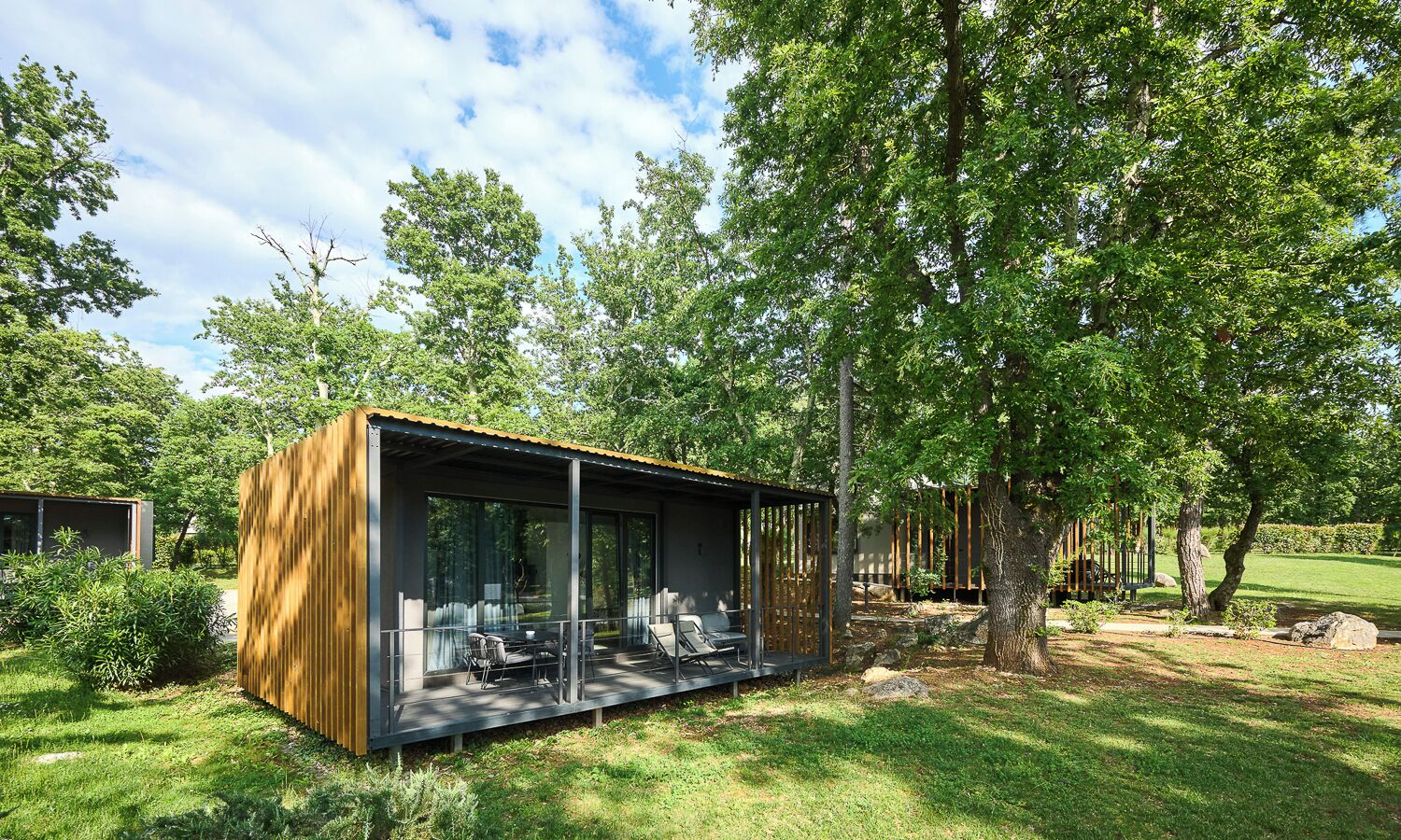 A modern outdoor structure with a glass enclosure, a seating area, and a wooden fence.