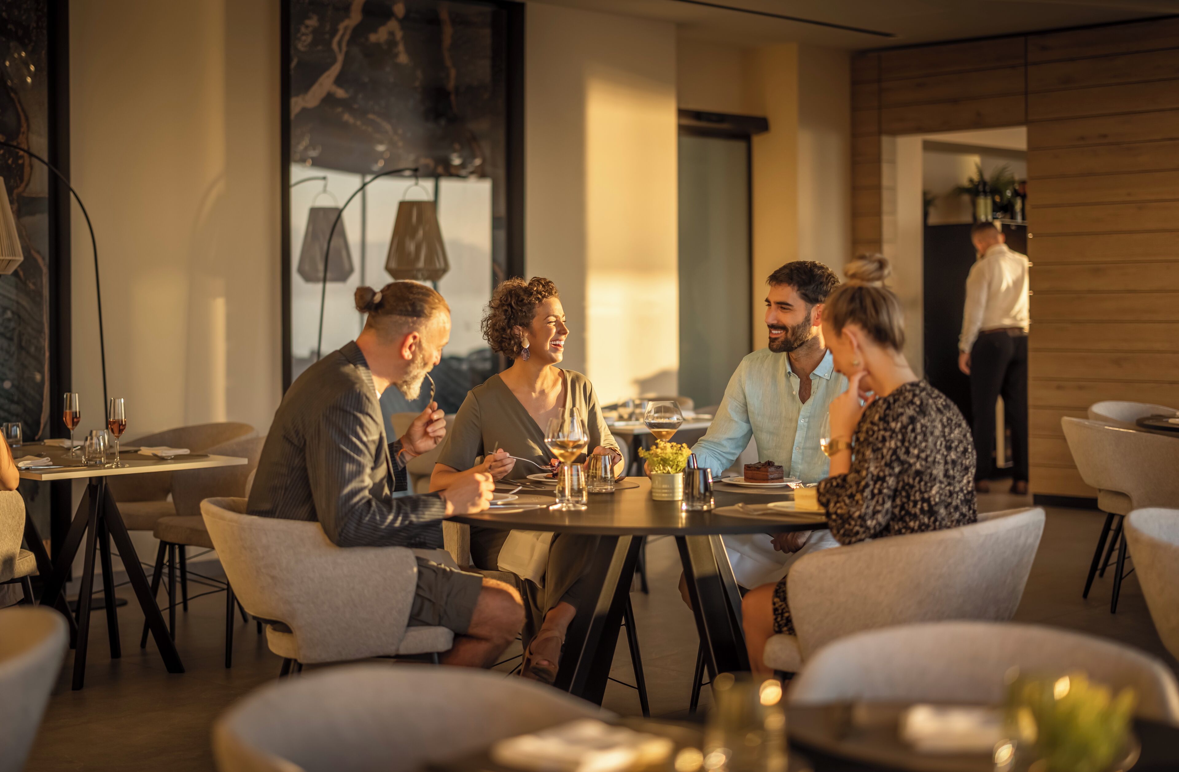 A group of people dining at a restaurant with round tables and modern decor.