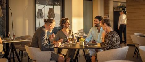 A group of people dining at a restaurant with round tables and modern decor.