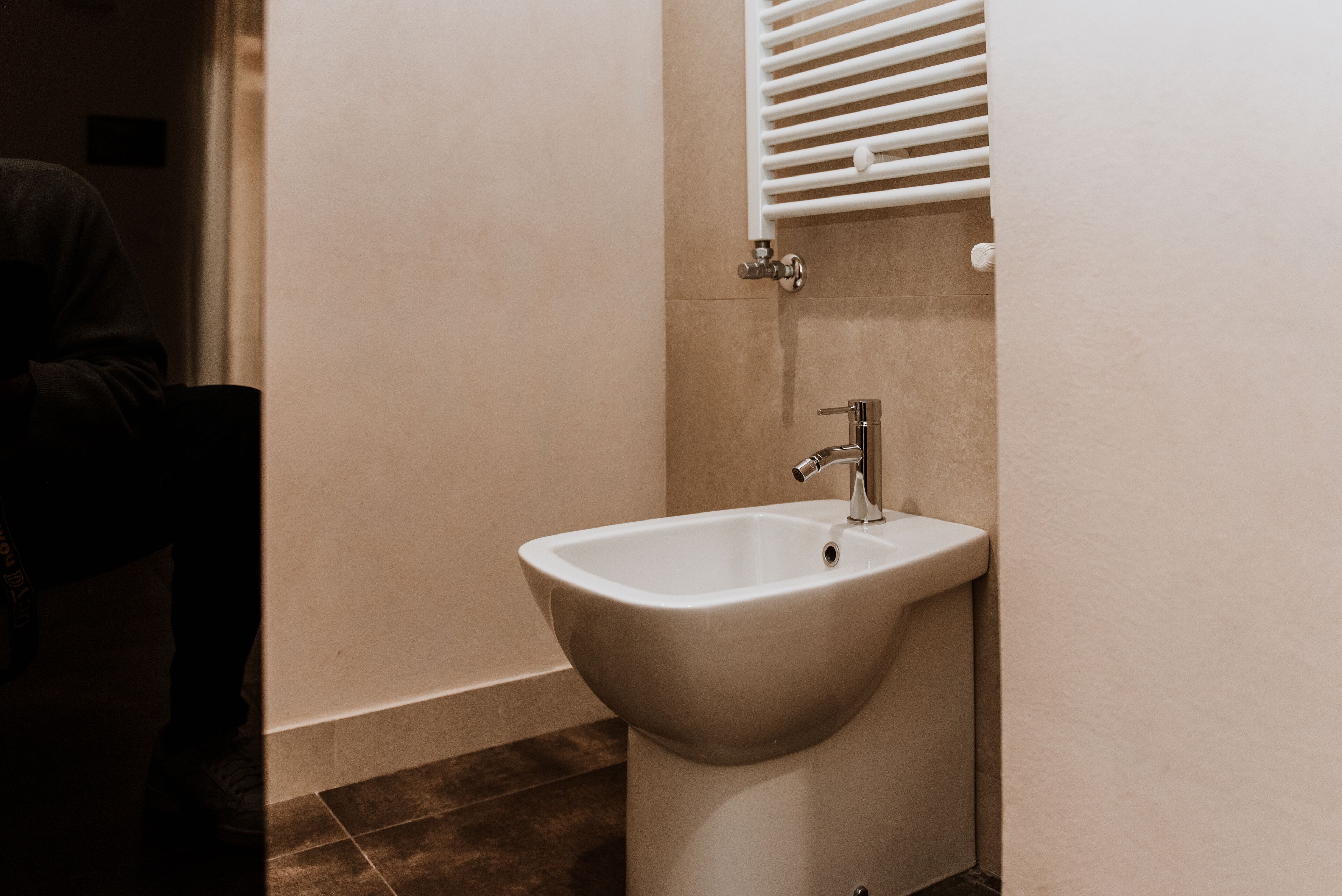 Uma casa de banho com uma pia branca, um porta-toalhas e um aquecedor fixo na parede.
