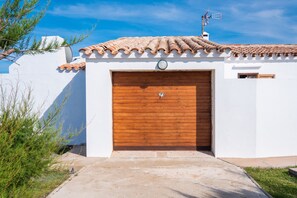 Un bâtiment avec un toit recouvert de tuiles, une porte de garage en bois et une petite fenêtre.