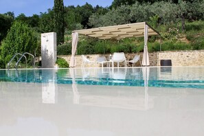 A swimming pool with a pergola, white chairs, and a stone wall. - Villa "Amazing Assisi" with Private Pool, Private Terrace & Wi-Fi (Assisi)