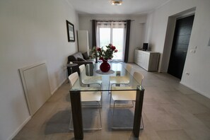 Uma sala de jantar moderna com mesa de vidro, cadeiras brancas e um vaso de flores.