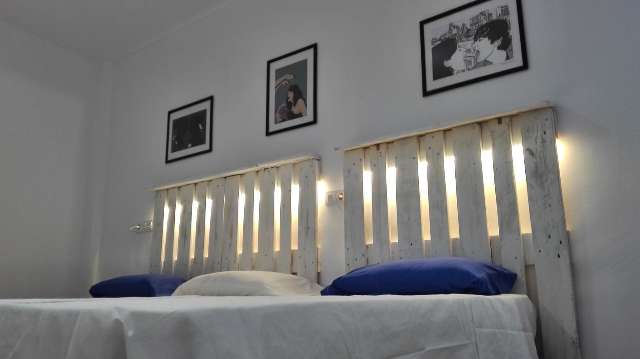 Een kamer met een bed, witte wanden en drie ingelijste foto's.