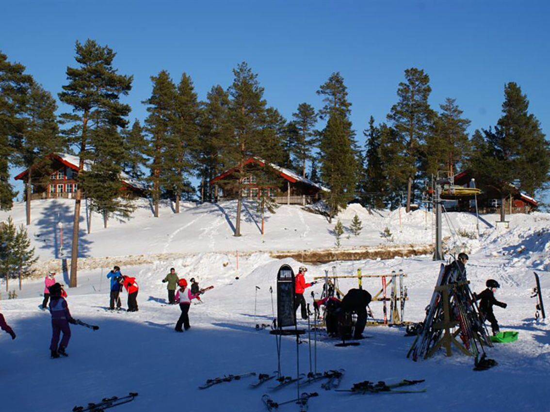 Une station de ski comprenant plusieurs bâtiments, des remontées mécaniques et des skieurs.