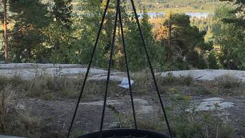Ein Hängesessel auf einer Holzterrasse mit Blick auf einen See und Berge im Hintergrund.