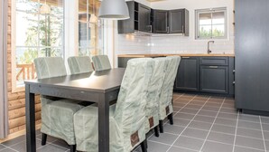 A modern kitchen with a dining area, featuring a large window, dark cabinetry, and a hanging light fixture. - Alpstigen 8b (Jarvso)