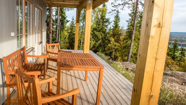 A wooden deck with a table and chairs, overlooking a forested area. - Alpstigen 8b (Jarvso)