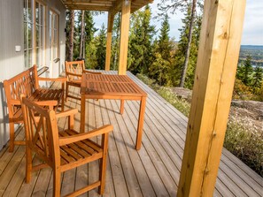 A wooden deck with a table and chairs, overlooking a forested area. - Alpstigen 8b (Jarvso)