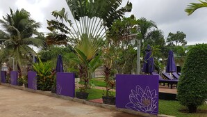 A garden area with a pathway, purple decorative panels, and lounge chairs. - White Lotus Resort (Siem Reap)