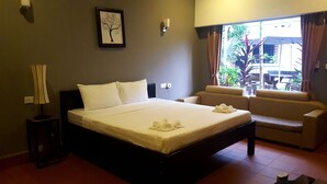 A hotel room with a bed, a sofa, a lamp, and a window with curtains. - White Lotus Resort (Siem Reap)