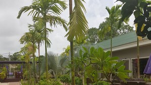 A paved walkway lined with small trees and benches, leading to a covered seating area with umbrellas. - White Lotus Resort (Siem Reap)
