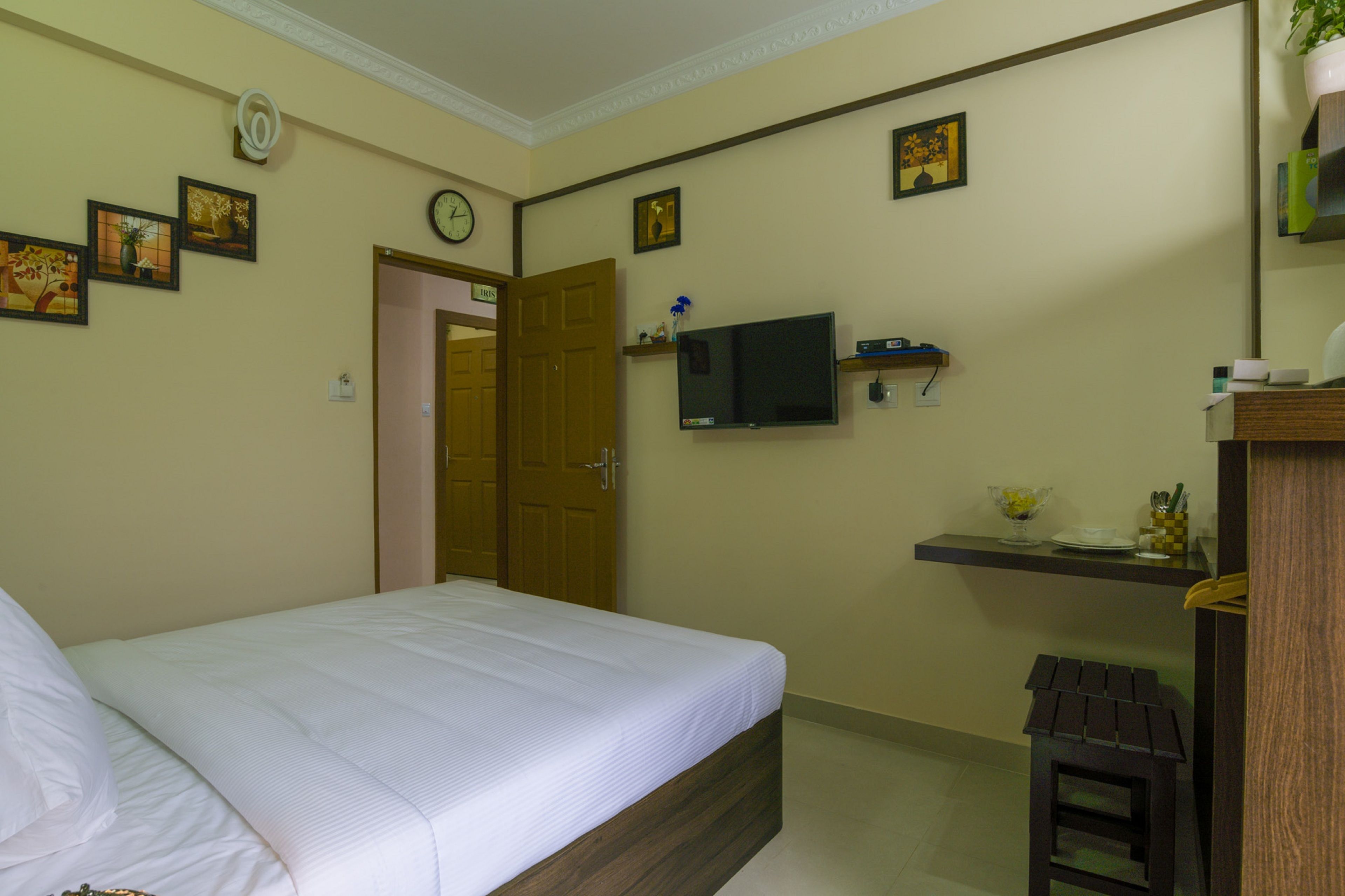 A bedroom with a bed, a TV, a small table, and a door.