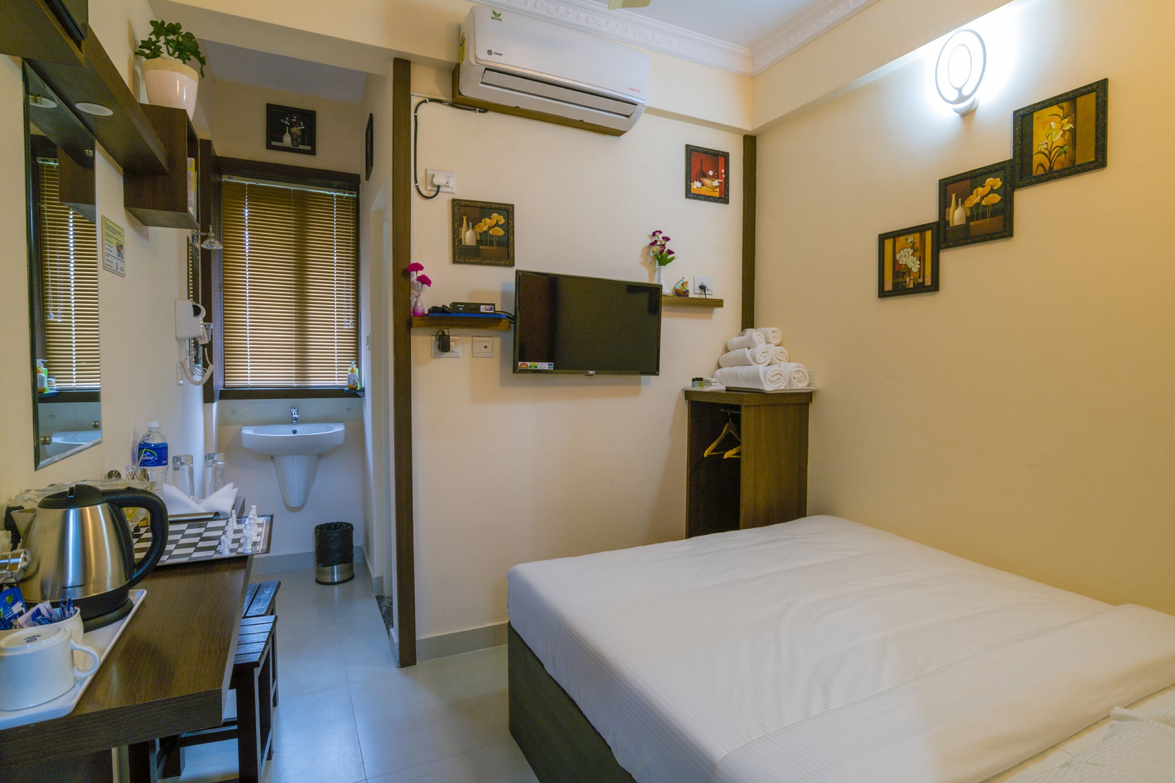 Une chambre d’hôtel équipée d’un lit, d’un bureau avec une bouilloire et des tasses, d’un lavabo et d’une télévision.