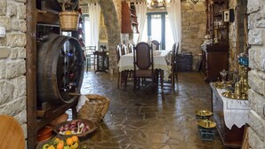 A rustic interior with stone walls, wooden beams, a stone floor, a dining area with a table and chairs, and barrels. - Majestic Chateau - Spectacular Seascapes & Pool (Kalamata)