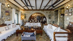 A cozy room with stone walls, wooden furniture, and a central seating area. - Majestic Chateau - Spectacular Seascapes & Pool (Kalamata)