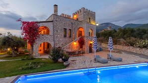 A stone building with a pool, outdoor seating, and a view of mountains. - Majestic Chateau - Spectacular Seascapes & Pool (Kalamata)