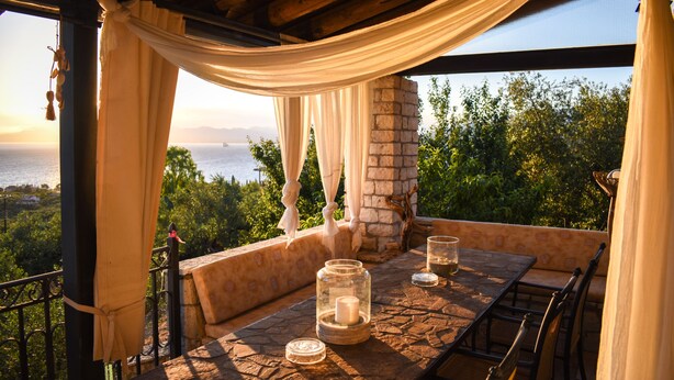 An outdoor dining area with a stone table, candles, and a view of the sea. - Majestic Chateau - Spectacular Seascapes & Pool (Kalamata)