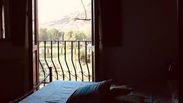 Ein schwach beleuchteter Raum mit einem Bett und einem Fenster mit Blick auf einen Balkon.