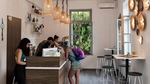 A modern kitchen with a wooden counter, hanging wicker light fixtures, and a view of greenery outside. - Kumba Hostel (Chania)