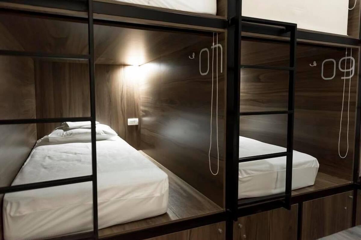 Quarto com beliche, paredes de madeira e uma cama de solteiro.