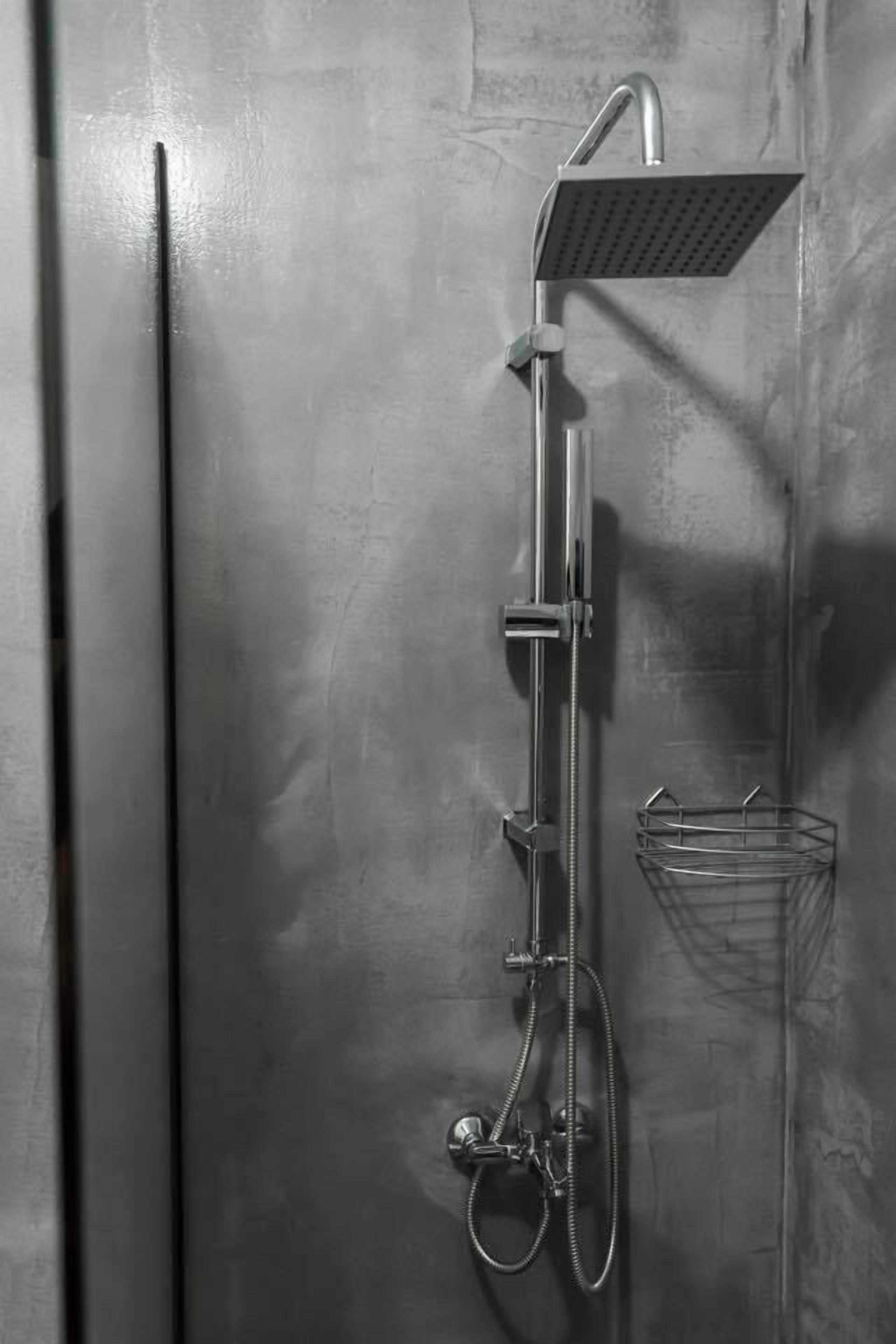 A modern shower with a handheld showerhead and a fixed showerhead, mounted on a wall with a textured surface.