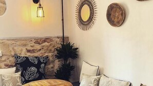 A cozy seating area with a stone wall, a hanging light fixture, and decorative plates on the wall. - Kumba Hostel (Chania)