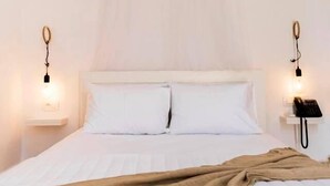 A bed with white bedding and a beige throw blanket, two bedside tables with lamps and a phone, and a white wall. - Kumba Hostel (Chania)
