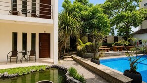 A modern building with a pool, outdoor seating, and a small water feature. - Satya Graha Hotel (Yogyakarta)
