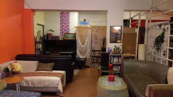 A cozy living room with a sofa, a small table, a bookshelf, and a television.