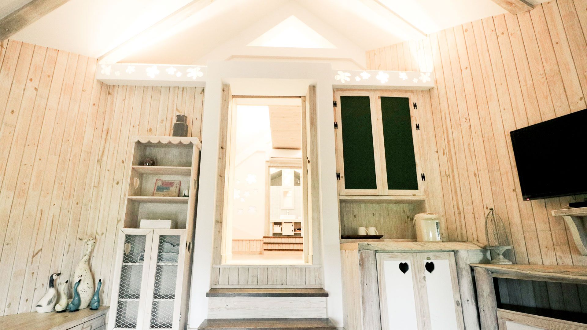 A cozy, rustic room with wooden walls and a built-in staircase leading to a bathroom.