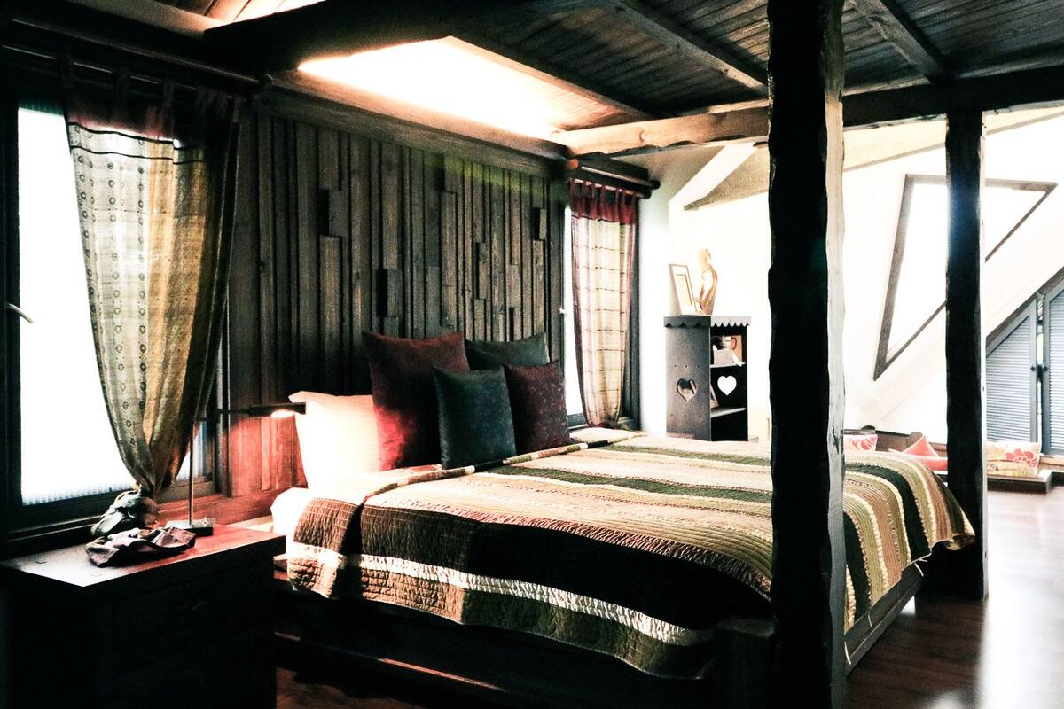 A bedroom with a bed, curtains, a nightstand, and a dresser.