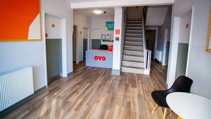 A reception area with a reception desk labeled "OYO," a staircase, and a chair.