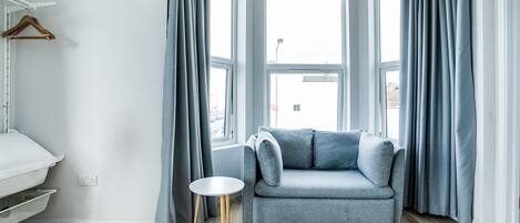A modern room with a grey sofa, a small round table, and a hanging wooden hanger.