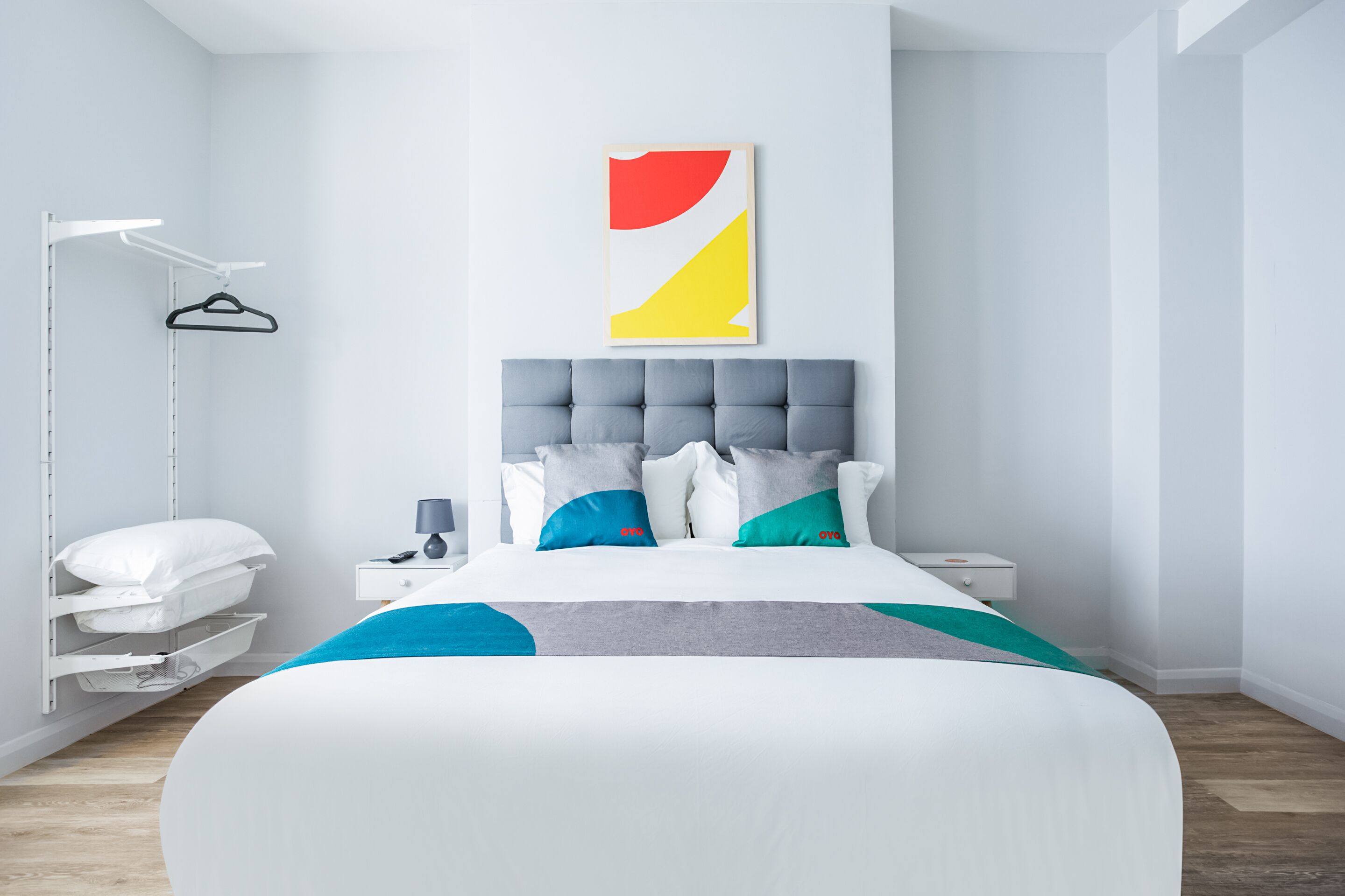 Un dormitorio moderno con una cama grande, una mesita de noche, una lámpara colgante y una obra de arte en la pared.