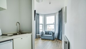 Una cocina moderna con lavavajillas incorporado, un lavabo y un ventanal con cortinas.
