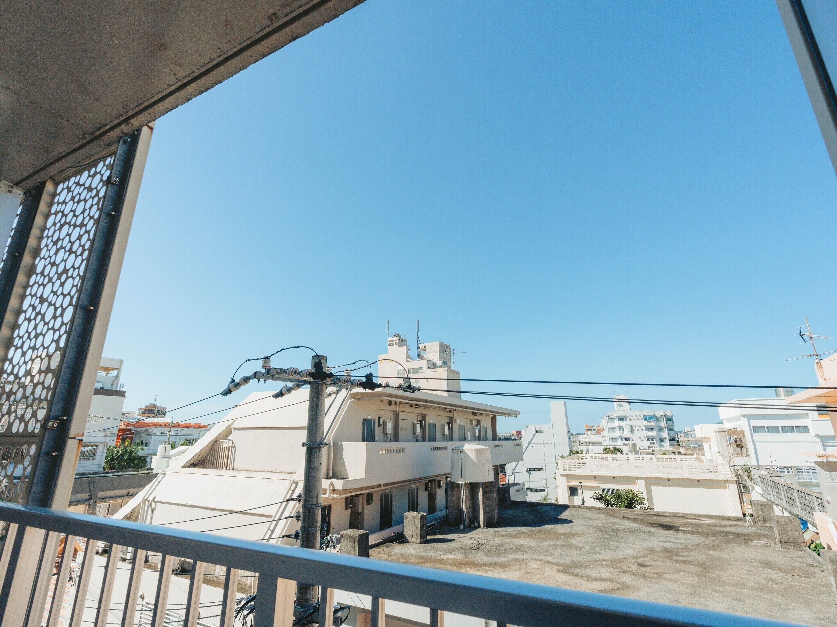 A residential building with a flat roof, visible utility lines, and a clear sky.