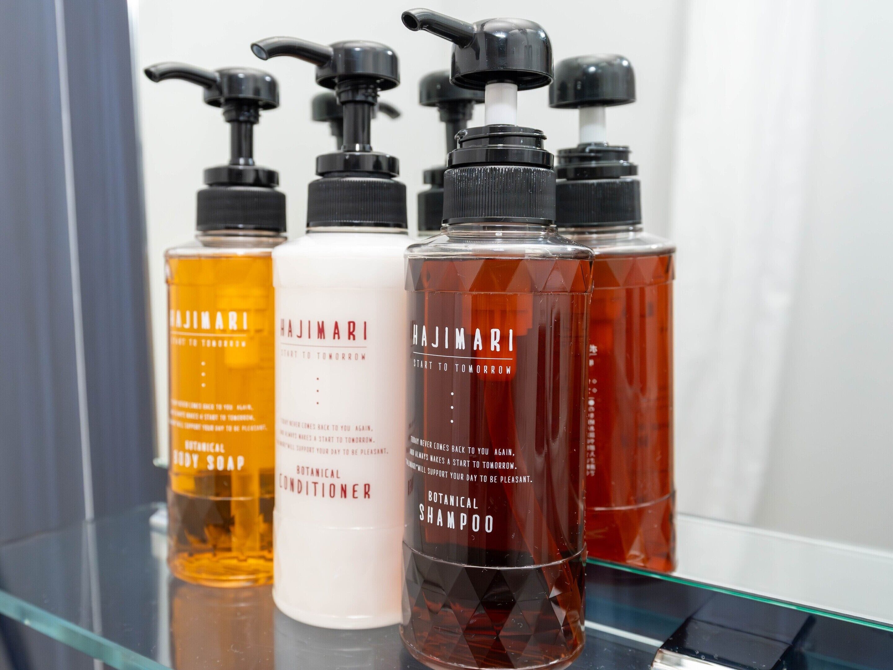 Four Hajimari hair care products on a glass shelf.