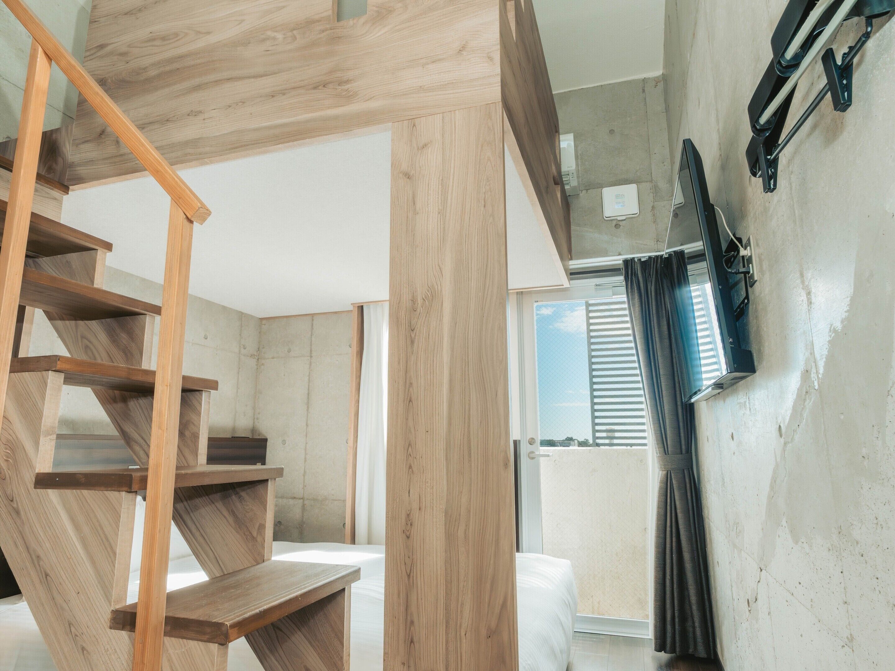 A modern interior with a wooden staircase, a bed, and a window with curtains.