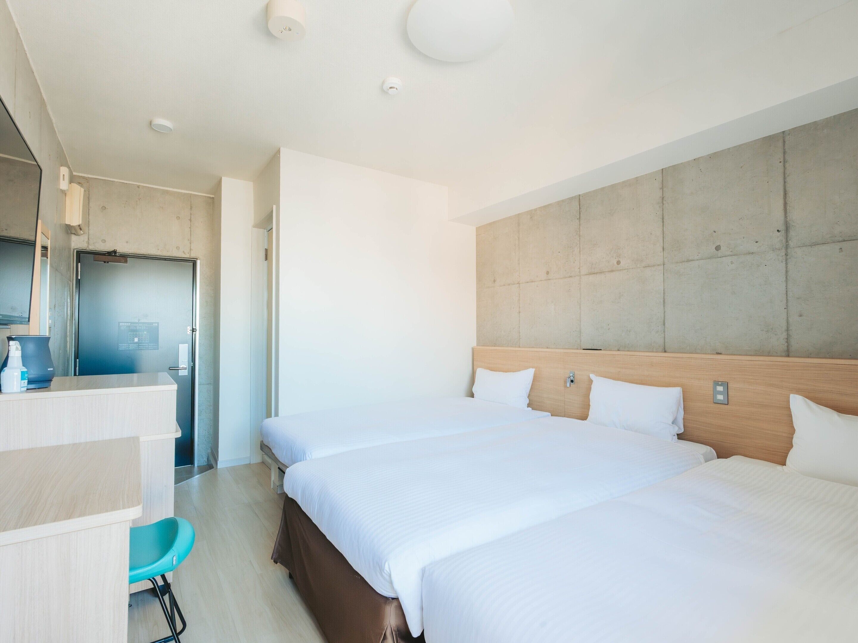 Une chambre d’hôtel avec deux lits, un bureau, une chaise et une grande fenêtre.