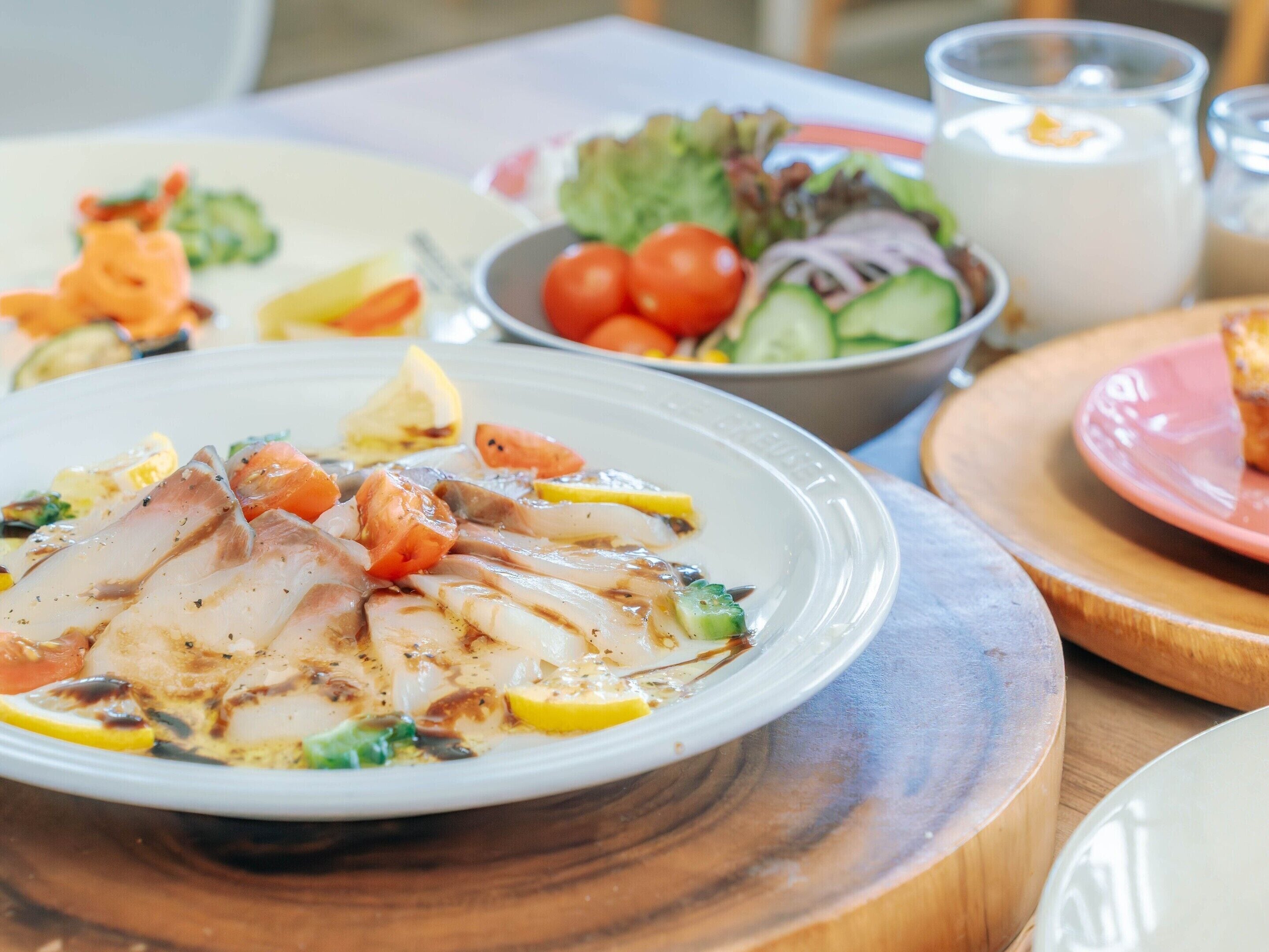 Une table à manger avec une assiette de nourriture, un saladier rempli de salade et un verre de lait.