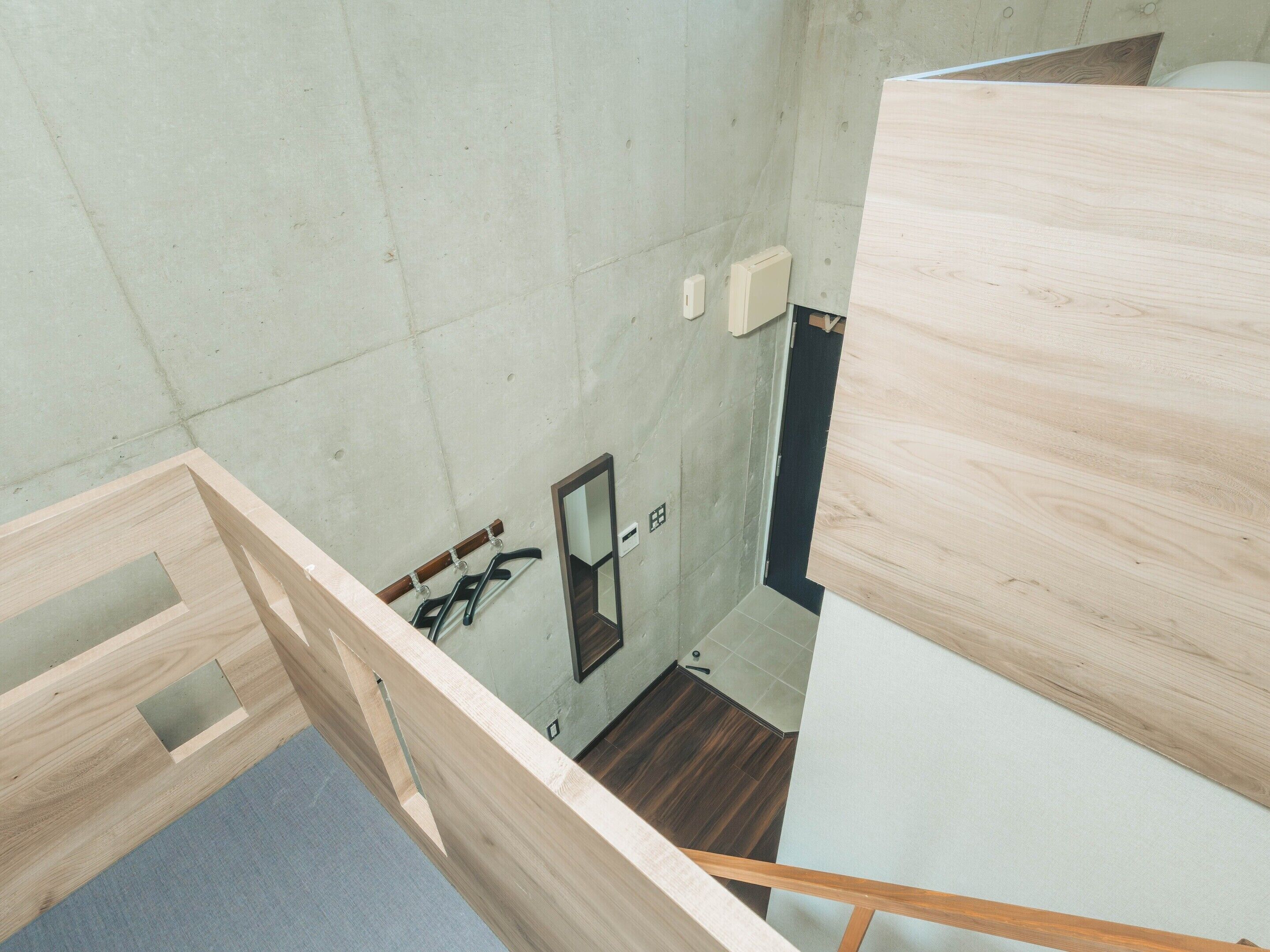 Ein Zimmer mit hohen Decken, Holzboden, einem kleinen Spiegel und einem Lichtschalter an der Wand.