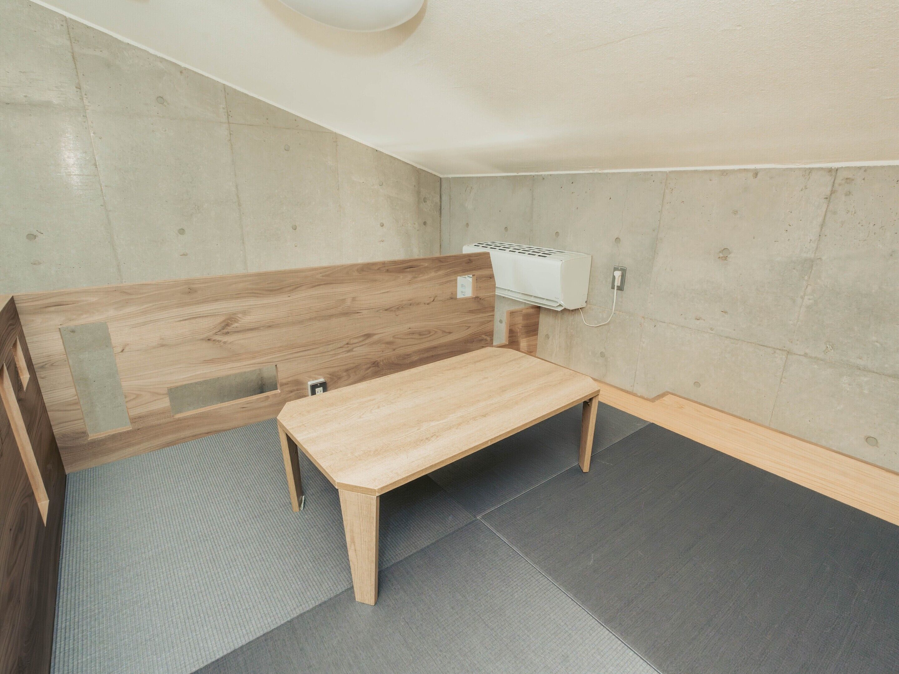 A room with a wooden bench, a small table, and a wall-mounted air conditioning unit.