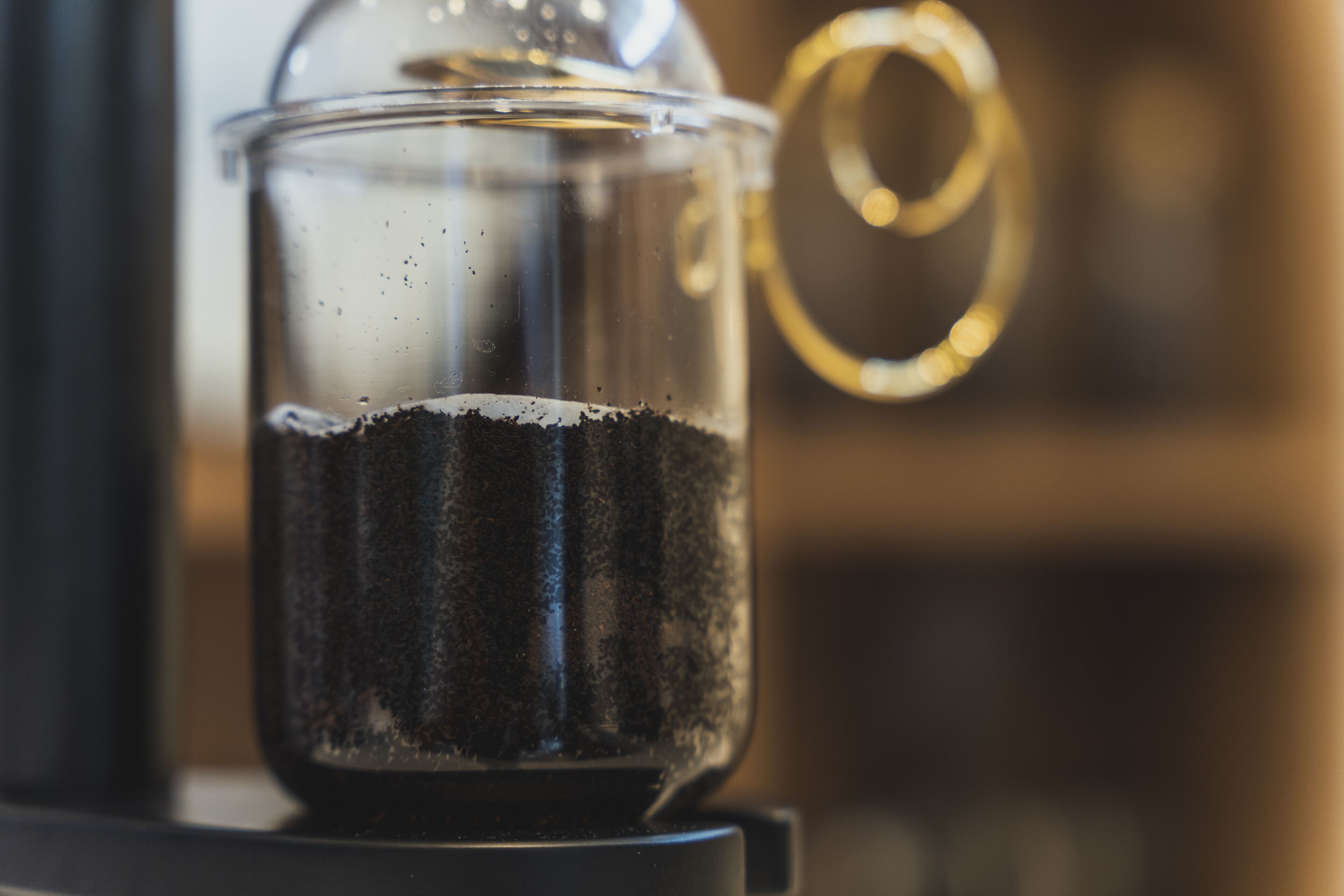 Une machine à café dotée d’un récipient en verre transparent et d’un manche métallique.