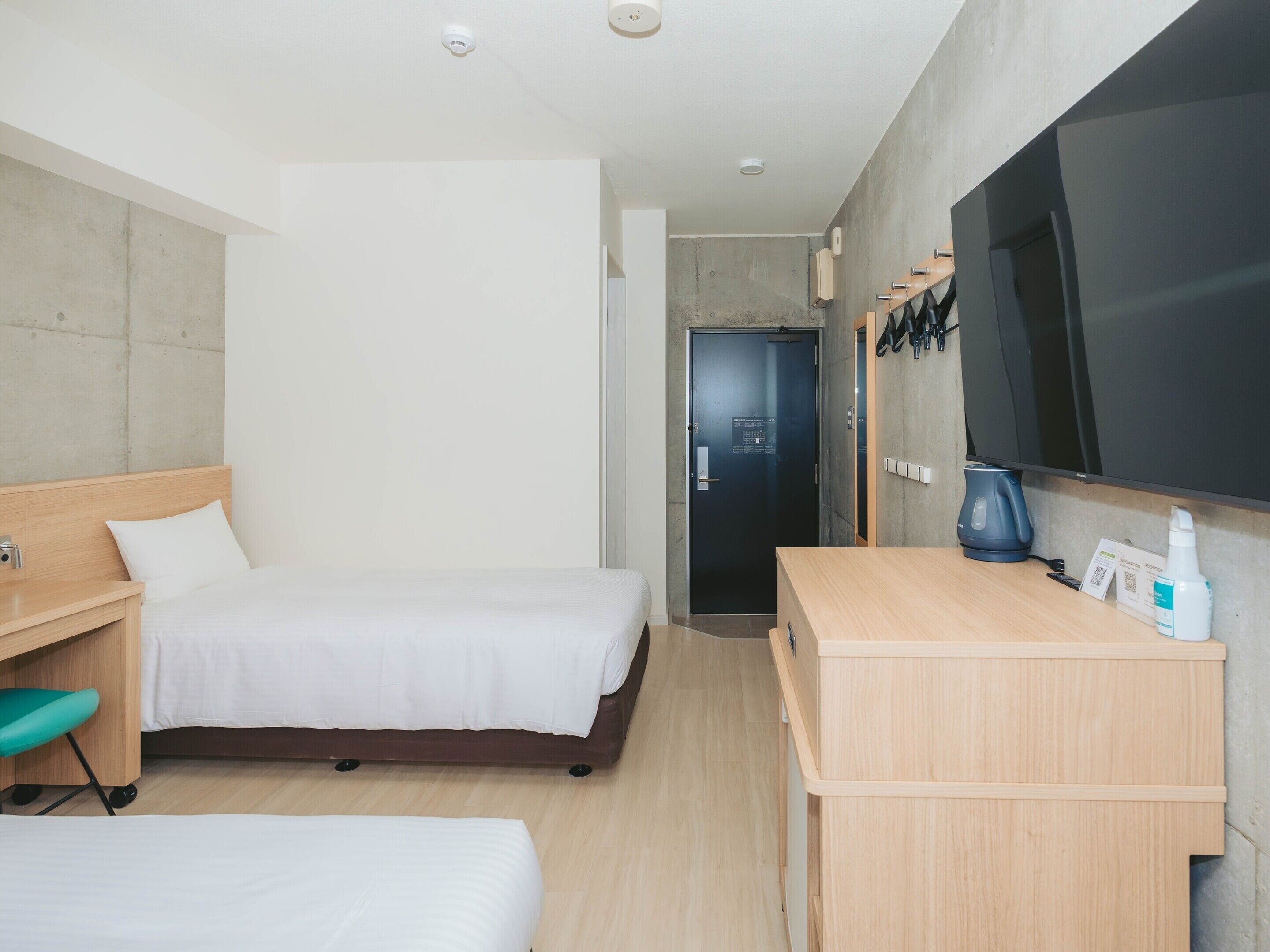 Een hotelkamer met een bed, een bureau, een stoel, een televisie en een deur.