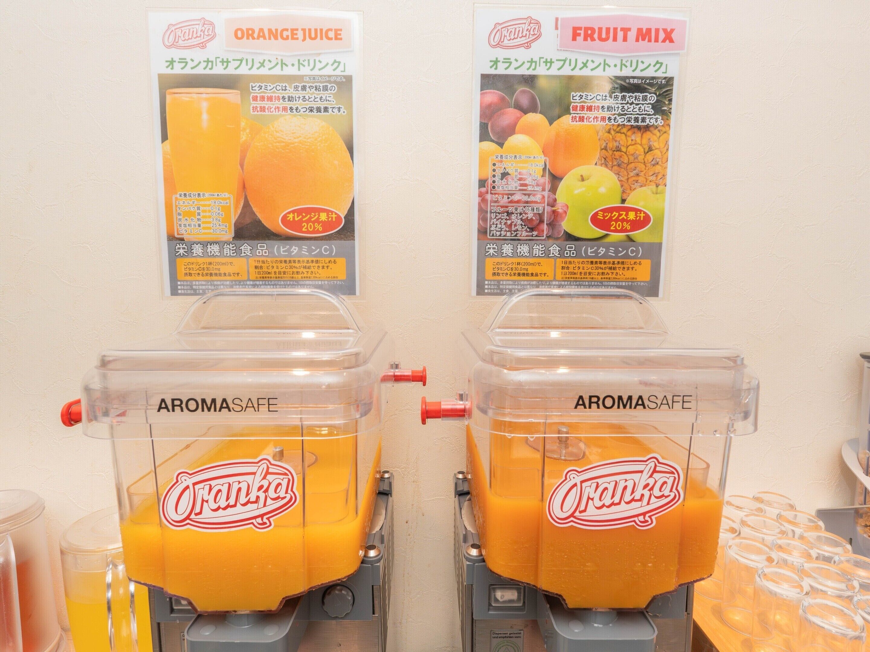 Dos dispensadores etiquetados 'ORANGE JUICE' y 'FRUIT MIX' con jugo de naranja fluyendo.