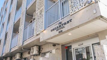 A hotel with a sign reading 'The Breakfast Hotel.' It features multiple balconies with decorative railings and air conditioning units installed on the exterior.