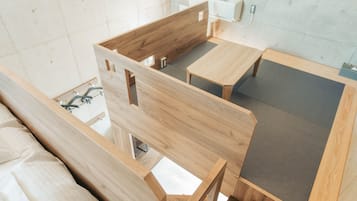 A room with a bed, a wooden bench, a small table, and a wall-mounted air conditioner.