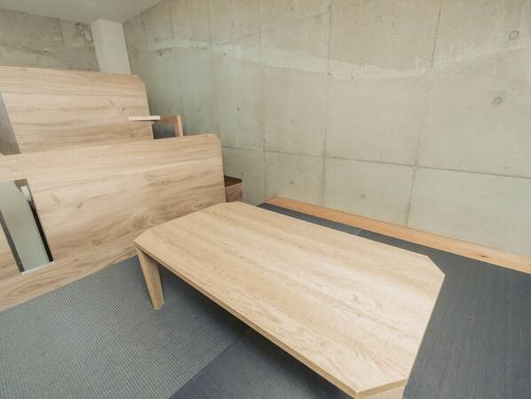 A room with a wooden bench, a small table, and a concrete wall.
